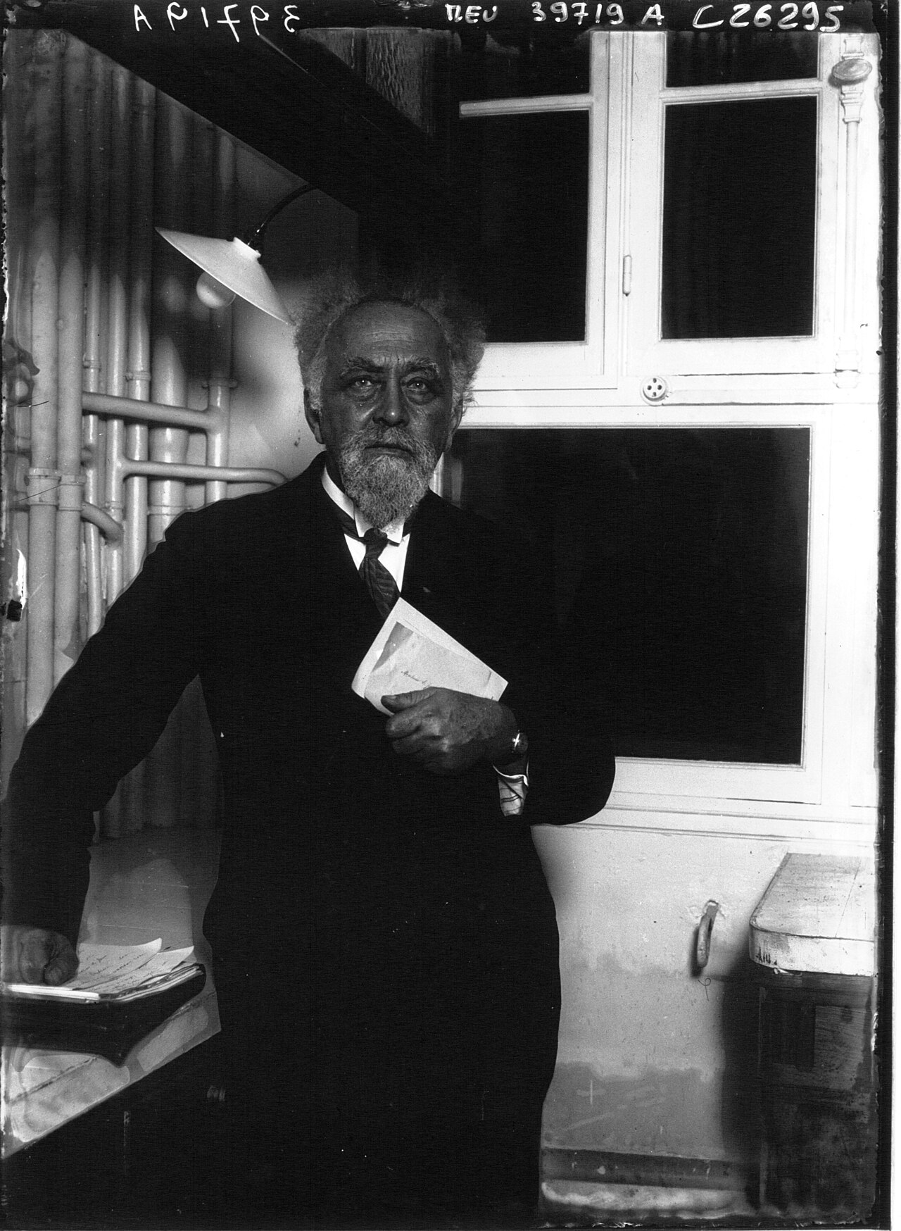 Jean Perrin, cheveux en bataille et barbe blanche, debout dans son laboratoire en 1926